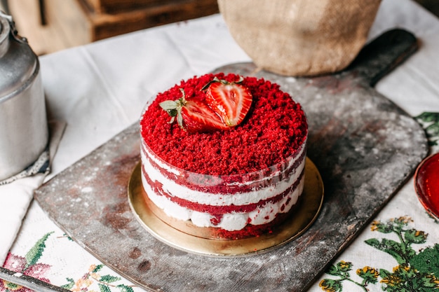 Una vista frontal pastel de frutas rojas decoradas con fresas redondas con crema deliciosa dulce celebración de cumpleaños en el escritorio marrón