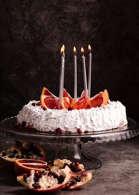Vista frontal del pastel con velas y frutas