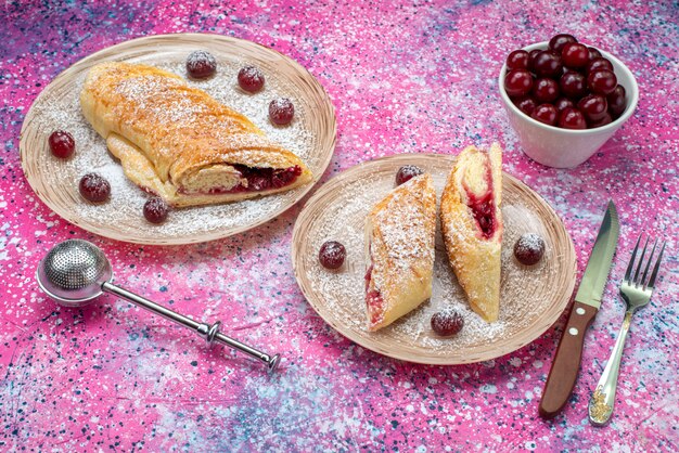 Vista frontal de pasteles de cerezas deliciosas y dulces en rodajas con cerezas agrias frescas dentro de la placa