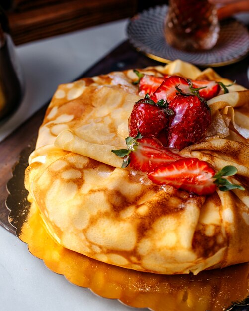 Vista frontal pasteles sabrosos con rodajas de fresas rojas frescas en el piso blanco