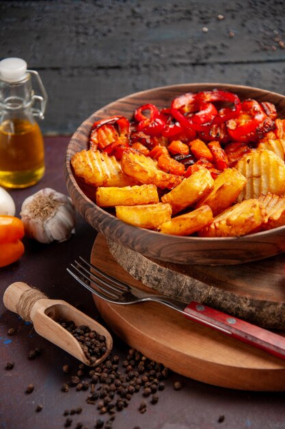 Vista frontal de patatas al horno con verduras cocidas en el espacio oscuro