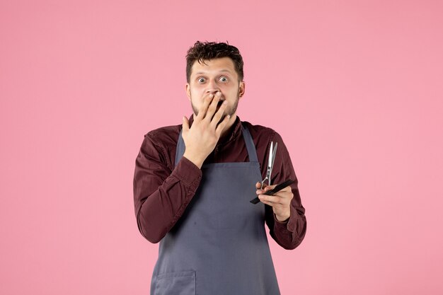 Vista frontal de la peluquería masculina con cepillo y tijeras sobre fondo de color rosa