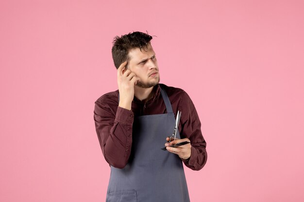 Vista frontal de la peluquería masculina con cepillo y tijeras sobre fondo de color rosa