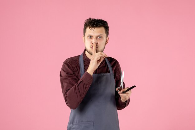 Vista frontal de la peluquería masculina con cepillo y tijeras sobre fondo de color rosa