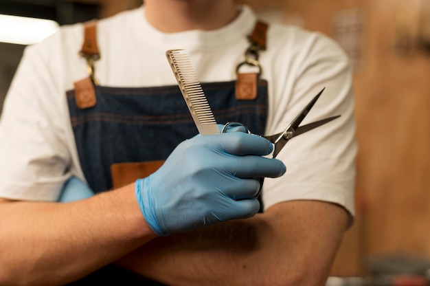 Vista frontal del peluquero masculino con tijeras en la barbería