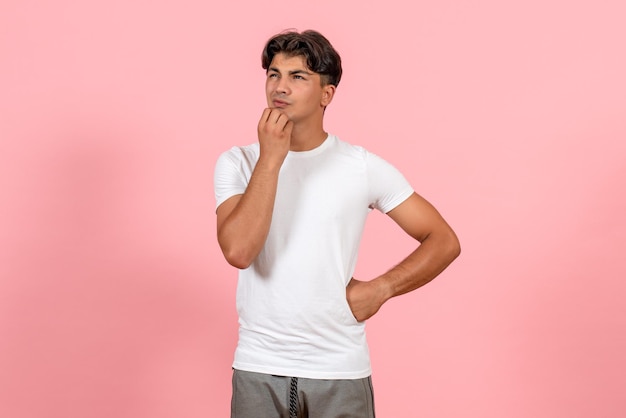 Vista frontal del pensamiento masculino joven en camiseta blanca sobre fondo rosa