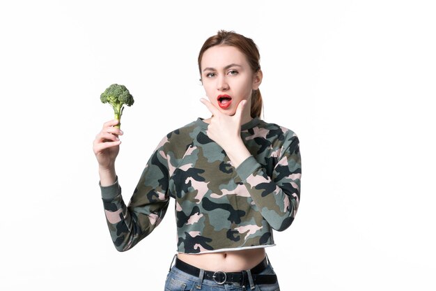 Vista frontal pensando en mujeres jóvenes con brócoli verde sobre blanco
