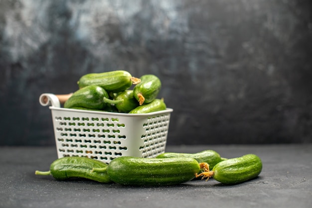 Vista frontal de los pepinos verdes frescos dentro de la cesta sobre fondo oscuro alimentos saludables foto ensalada color comida