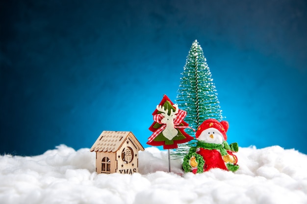 Vista frontal pequeña casa de madera de juguetes de Navidad sobre fondo azul.