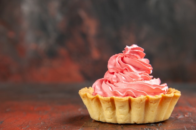 Vista frontal pequeña tarta con crema pastelera rosa en lugar libre de mesa rojo oscuro