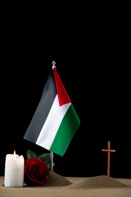 Vista frontal de la pequeña tumba con bandera palestina en negro