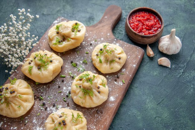 Vista frontal pequeñas albóndigas crudas con salsa de tomate en la mesa azul oscuro masa de carne plato de cocina pastel cena comida cocinar