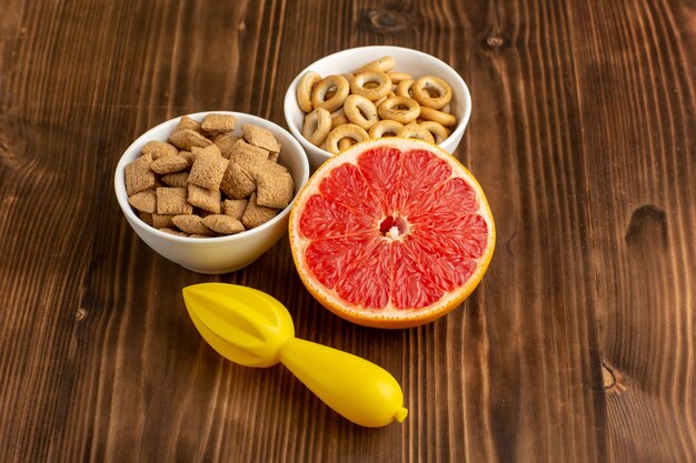 Vista frontal pequeñas galletas de almohada con galletas saladas y pomelo en el escritorio marrón