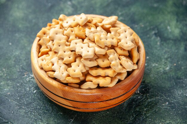 Vista frontal pequeñas galletas dentro de la placa sobre fondo oscuro color crujiente bocadillo pan de sal bizcocho de alimentos cips