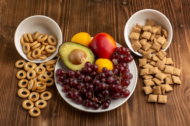 Vista frontal pequeñas galletas y galletas saladas con frutas en un escritorio de madera marrón