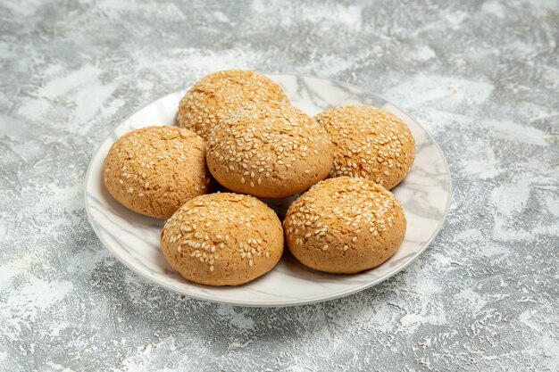 Vista frontal de las pequeñas galletas suaves postre delicioso para el té dentro de la placa en la pared blanca pastel de galletas hornear galletas dulces de azúcar