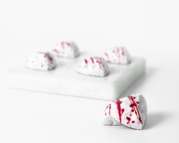 Vista frontal de pequeñas piedras blancas diseñadas con líneas rojas aisladas en el escritorio blanco