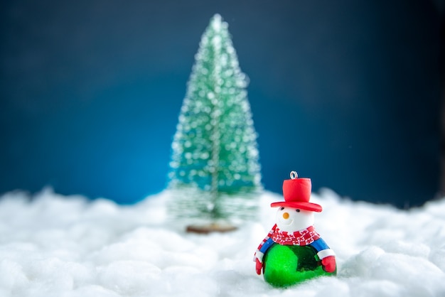 Vista frontal pequeño árbol de Navidad de muñeco de nieve sobre superficie blanca azul