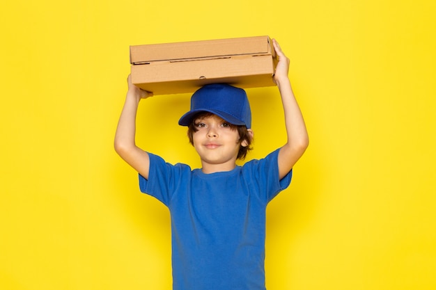 Una vista frontal pequeño mensajero lindo en camiseta azul gorra azul jeans grises