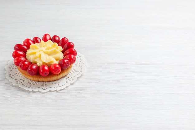 Vista frontal pequeño pastel cremoso con cornejos en un escritorio blanco postre pastel de color crema de frutas