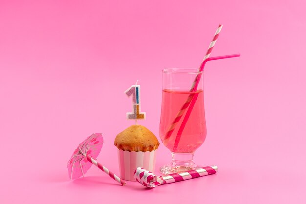 Vista frontal de un pequeño pastel de cumpleaños con silbato de cumpleaños rosa, jugo con paja en rosa, color de celebración de galletas