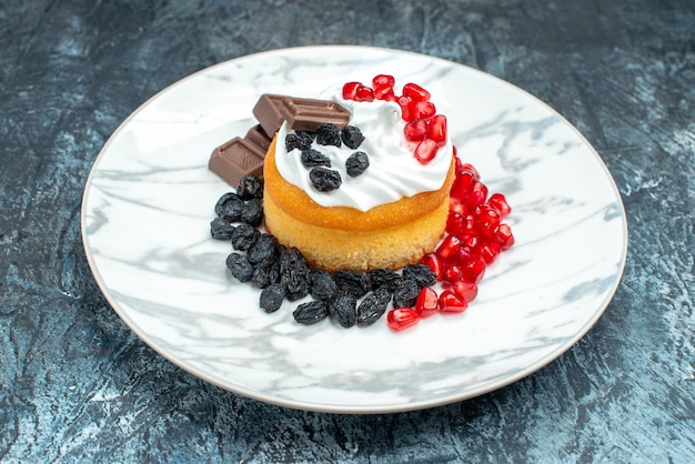 Foto gratuita vista frontal pequeño pastel delicioso con chocolate y pasas sobre fondo claro-oscuro