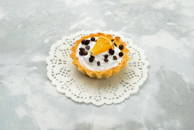 Vista frontal pequeño pastel delicioso con crema y frutos secos en la superficie de luz pastel dulce masa de azúcar
