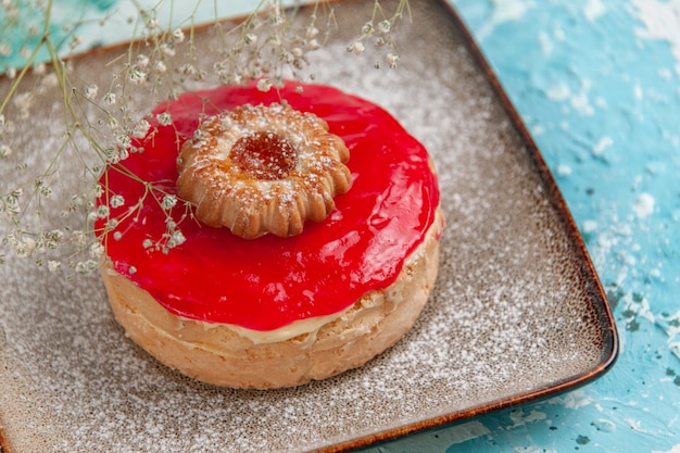 Foto gratuita vista frontal pequeño pastel delicioso con crema roja sobre superficie azul claro