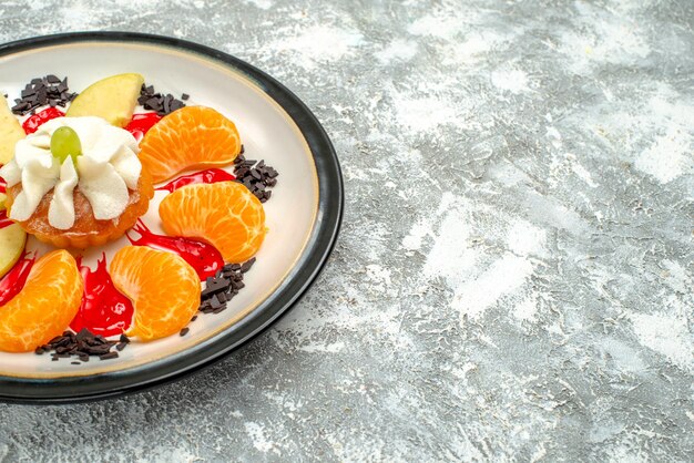 Vista frontal pequeño pastel con rodajas de manzanas y mandarinas dentro de la placa sobre fondo blanco pastel de frutas dulces galleta de azúcar cookie