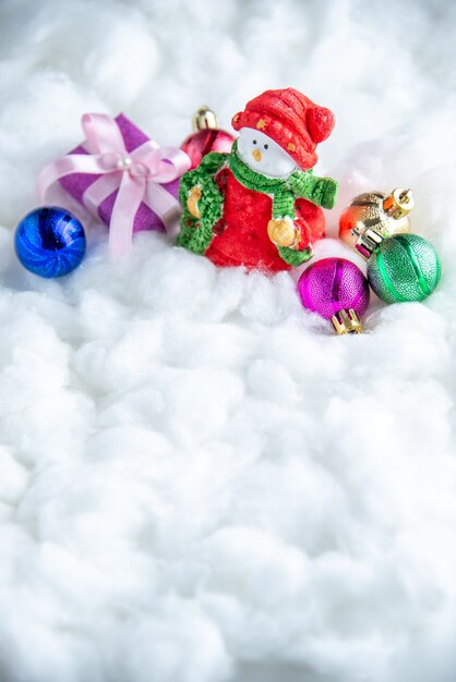 Vista frontal pequeños juguetes de árbol de Navidad de muñeco de nieve sobre superficie blanca aislada