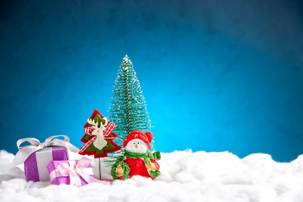 Vista frontal pequeños juguetes de Navidad pequeños regalos sobre fondo azul.