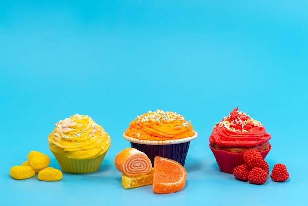 Vista frontal de pequeños pasteles coloridos con dulces de mermelada en azul, caramelo de color galleta