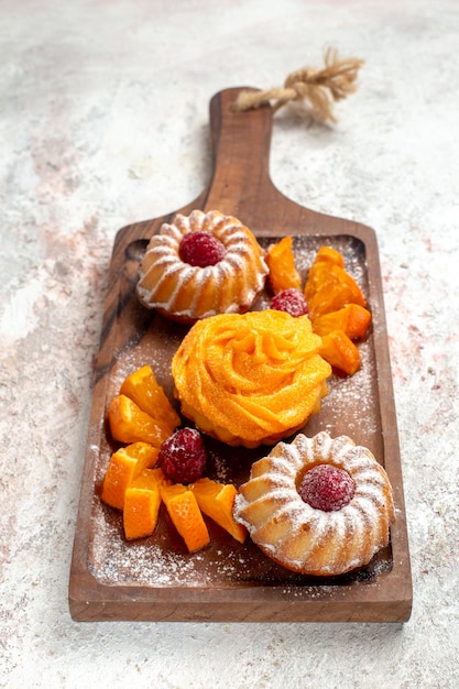 Foto gratuita vista frontal de pequeños pasteles postre perfecto para el té con frutas sobre fondo blanco pastel de té postre postre galleta dulce