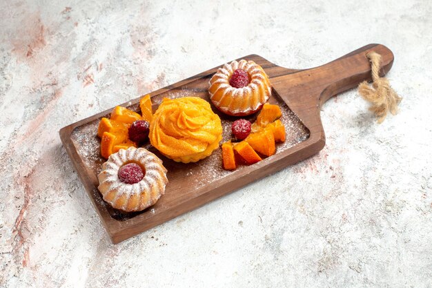 Vista frontal de pequeños pasteles postre perfecto para el té con frutas sobre fondo blanco pastel de té postre postre galleta dulce