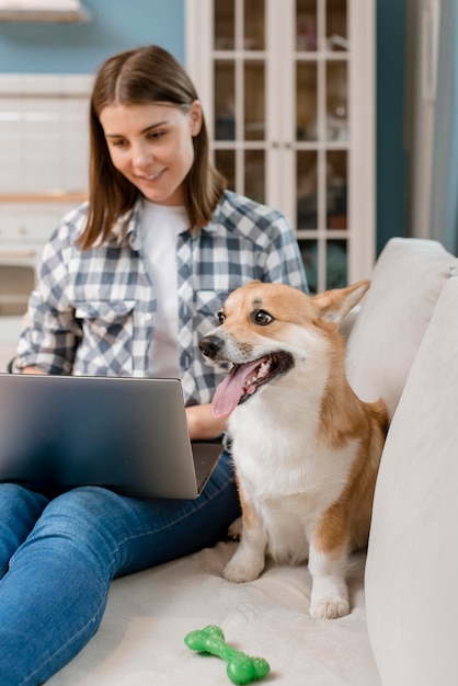 Foto gratuita vista frontal del perro con juguete y mujer con laptop en sofá