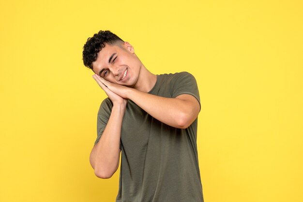 Vista frontal de una persona hombre sonriente pone su cabeza sobre sus manos