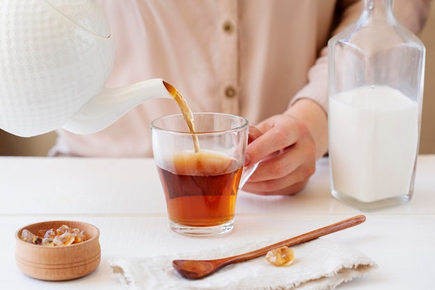 Vista frontal de la persona que prepara té con leche