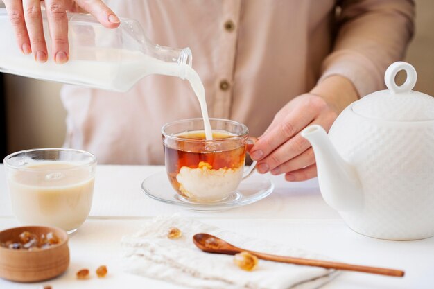 Vista frontal de la persona que prepara té con leche