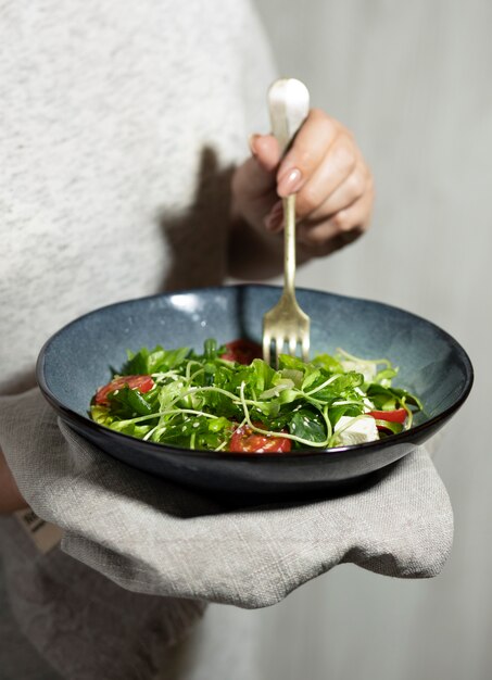 Vista frontal de la persona que sostiene un plato de ensalada.