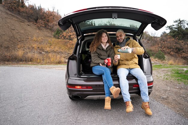 Vista frontal de personas sentadas en el baúl del auto