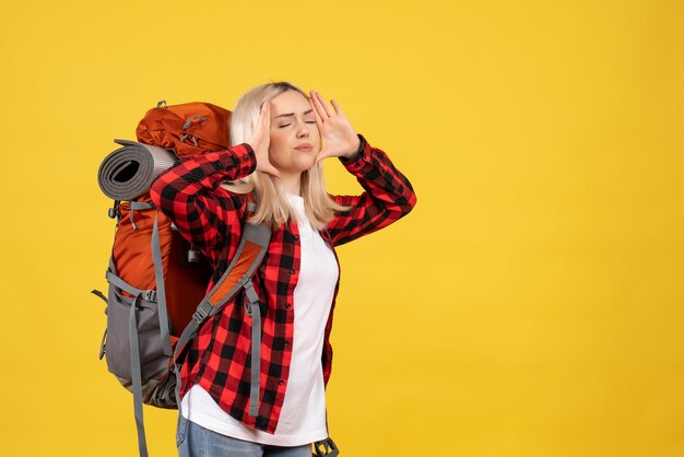 Vista frontal perturbada chica rubia con su mochila sosteniendo su cabeza