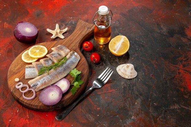 Vista frontal de pescado crudo en rodajas con aros de cebolla sobre carne de ensalada de color marisco oscuro