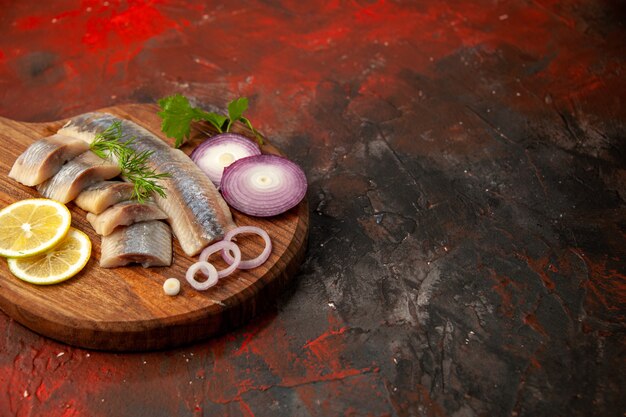 Vista frontal de pescado fresco en rodajas con aros de cebolla y limón en una comida oscura, carne, mariscos, bocadillo, fotografía en color, lugar libre