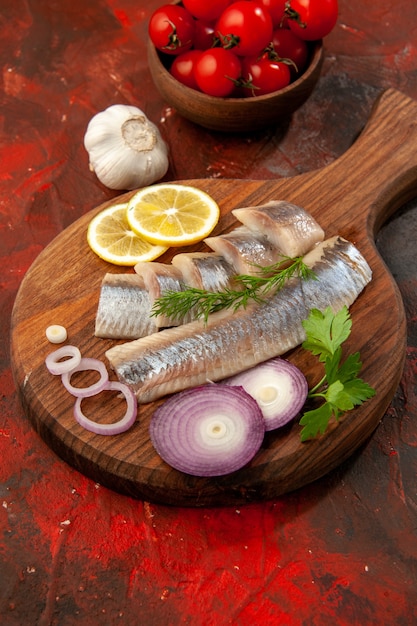Vista frontal de pescado fresco en rodajas con aros de cebolla y tomates en mariscos de color oscuro de comida de aperitivo de carne