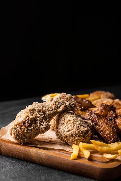 Vista frontal de las piernas de pollo frito con papas fritas y espacio de copia