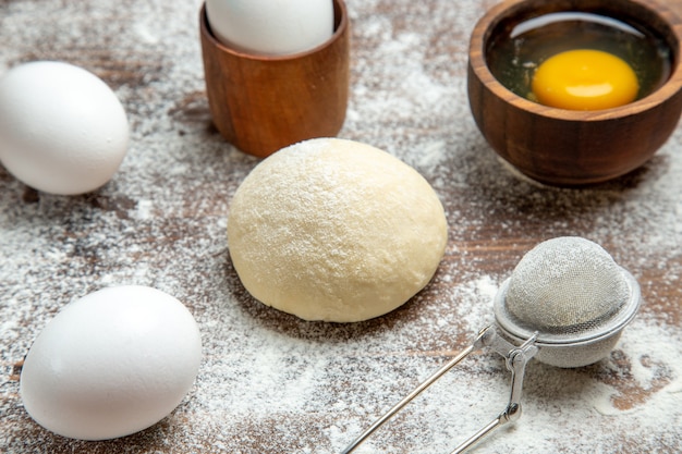 Vista frontal de la pieza de masa cruda con huevos y harina en la mesa de masa de masa cruda