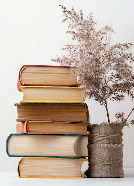 Vista frontal de la pila de libros con jarrón y flores.