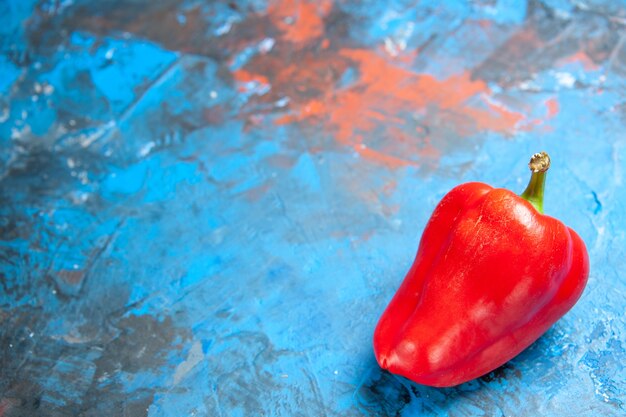 Vista frontal de pimiento rojo sobre una mesa azul