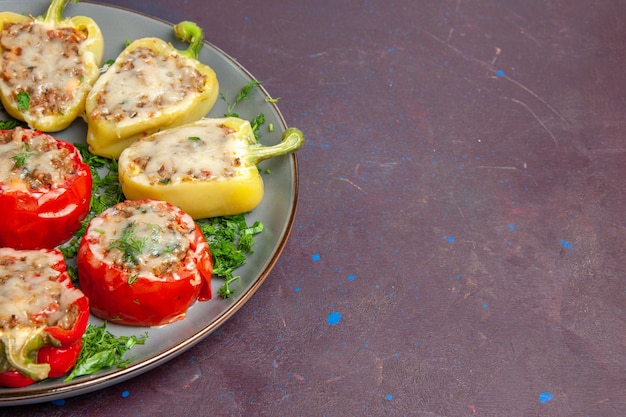 Vista frontal de pimientos horneados con queso verde y carne dentro de la placa en el piso oscuro hornear cena plato comida comida