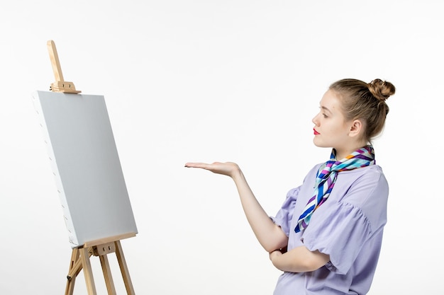 Vista frontal pintora femenina con caballete para pintar en la pared blanca dibujo arte foto artista pintura borla imagen